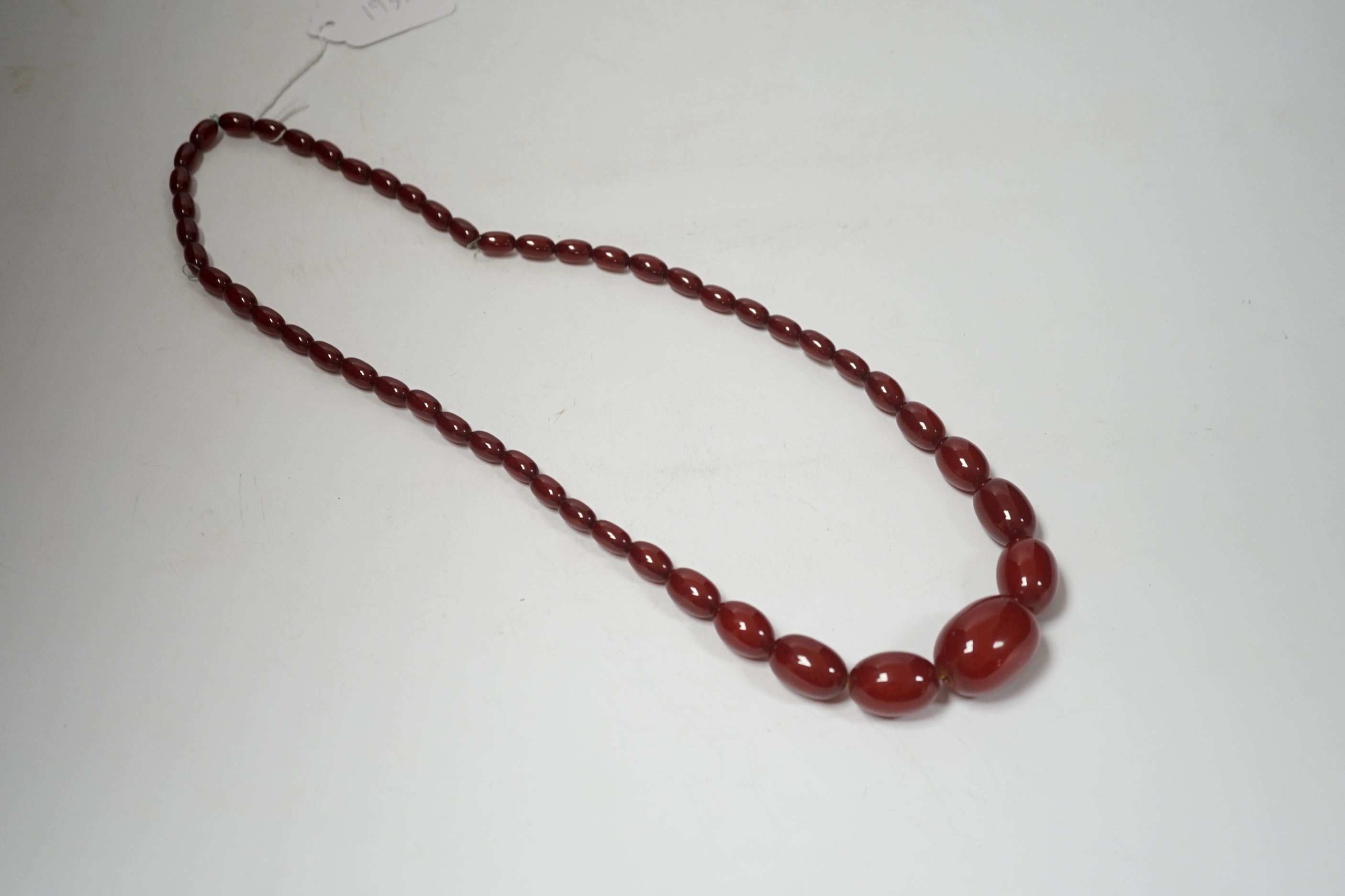 A single strand graduated oval simulated cherry amber bead necklace, 70cm, gross weight 63 grams.